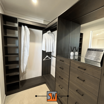 Well-organised walk-in wardrobe with shelves, hanging rods, and pull-out drawers.