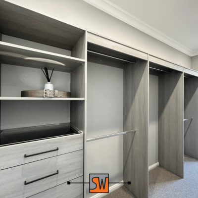 Well-organised walk-in wardrobe with shelves, hanging rods, and pull-out drawers.